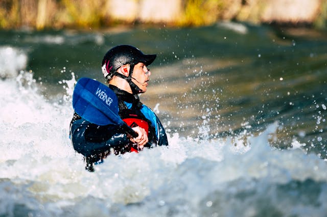 A kayak overturns in rough waters, spilling gear and paddles into the churning waves